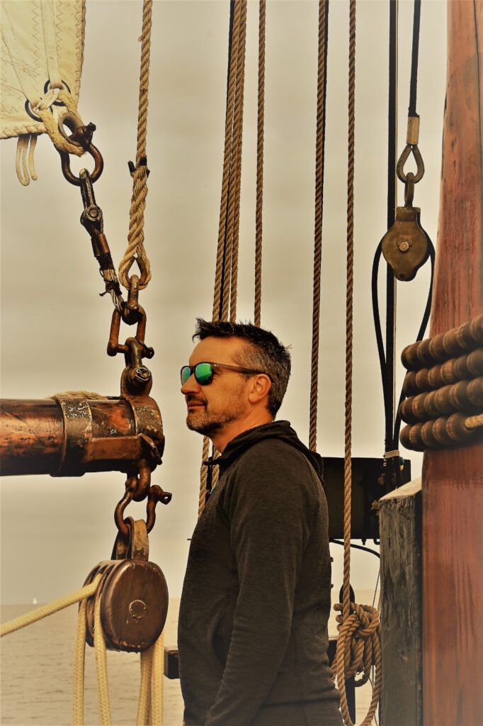 Man aan boord van klipper staat naast de mast