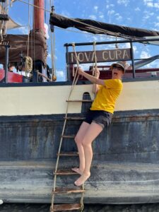 Vrouw staat op touwladder buiten boord van klipper nova cura