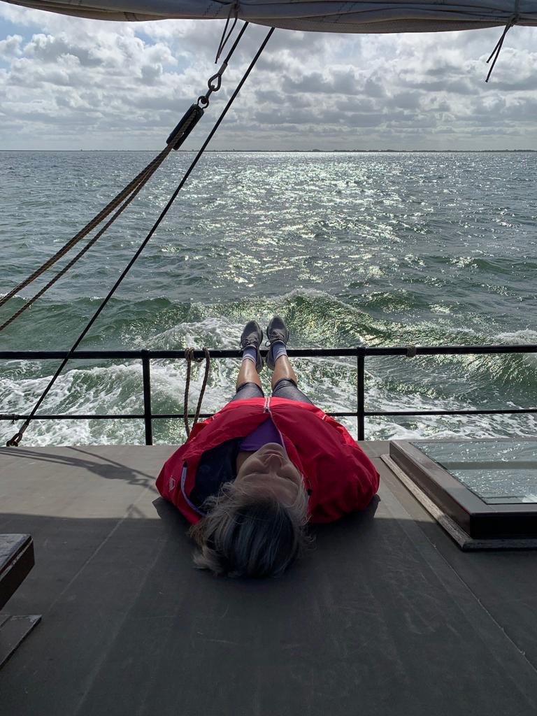 vrouw slaapt aan dek met waddenzee op achtergrond
